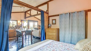 Une chambre à coucher avec un lit, une commode, un bureau et une chaise. Il y a une fenêtre avec des rideaux et une vue sur l’extérieur.