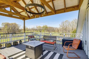 A covered deck with a wooden bench, a table, and a chair.
