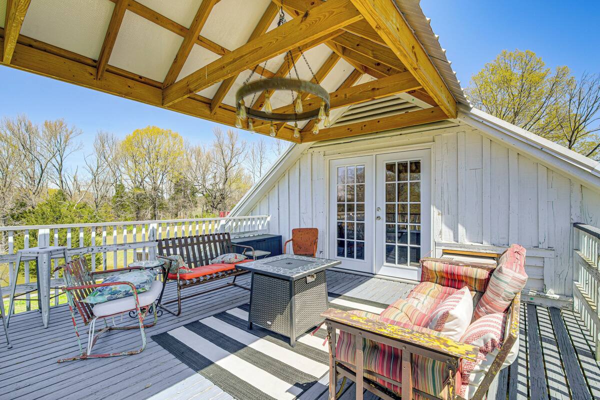 Une terrasse couverte, aménagée avec du mobilier d’extérieur, une table et un banc.