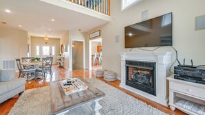A spacious living room with a fireplace, a television mounted on the wall, and a dining area with a table and chairs. - Lake Cumberland Home w/ Hot Tub & Game Room (Bronston)
