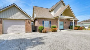 A two-story house with a garage, brick exterior, and a front porch. - Lake Cumberland Home w/ Hot Tub & Game Room (Bronston)