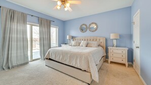 A bedroom with a large bed, two bedside tables with lamps, a ceiling fan, and a view through a window. - Lake Cumberland Home w/ Hot Tub & Game Room (Bronston)