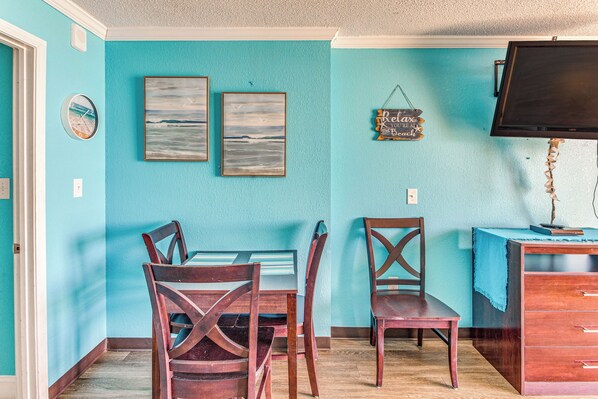 A dining area with a table and chairs, a television, and wall art. - Sun, Sand & Sea Views: Myrtle Beach Condo (Myrtle Beach)