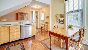 A kitchen with wooden cabinets, a dishwasher, and a dining table with chairs. - Walk to Beach: Cape May Home w/ Screened Patio! (Cape May)