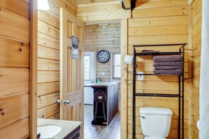 Een houten badkamer in een hut, met een wastafel, toilet en handdoekhouder.