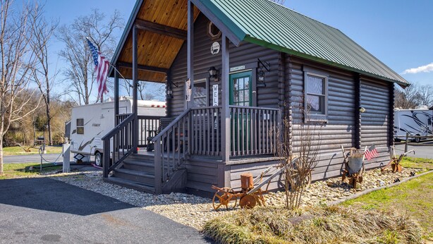 A log cabin with a porch, steps, and a small American flag. - Fire Pit + Pool Access: Cozy Cabin in Sevierville! (Sevierville)