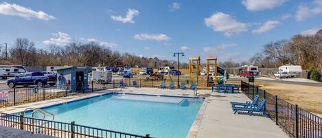 A swimming pool with a fenced deck, lounge chairs, and a lifeguard tower.