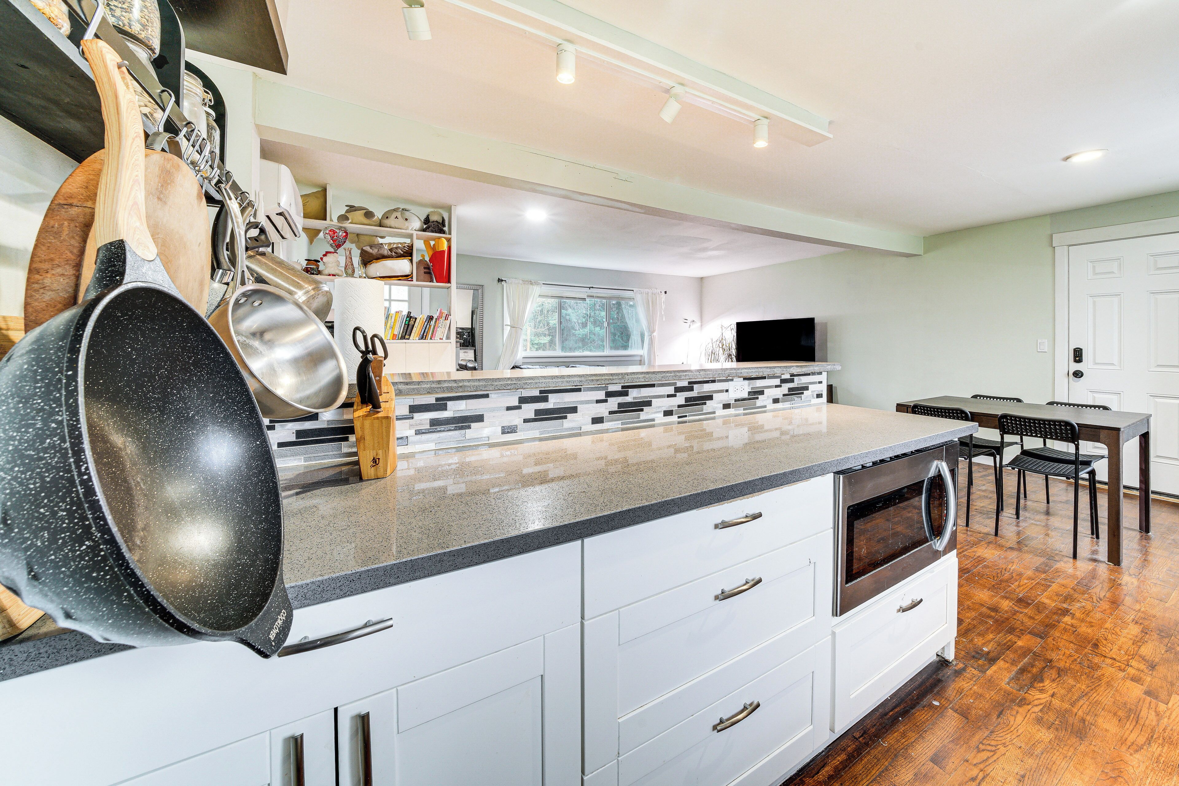 Une cuisine moderne avec des meubles blancs, un grand îlot central et un coin repas comprenant une table et des chaises.