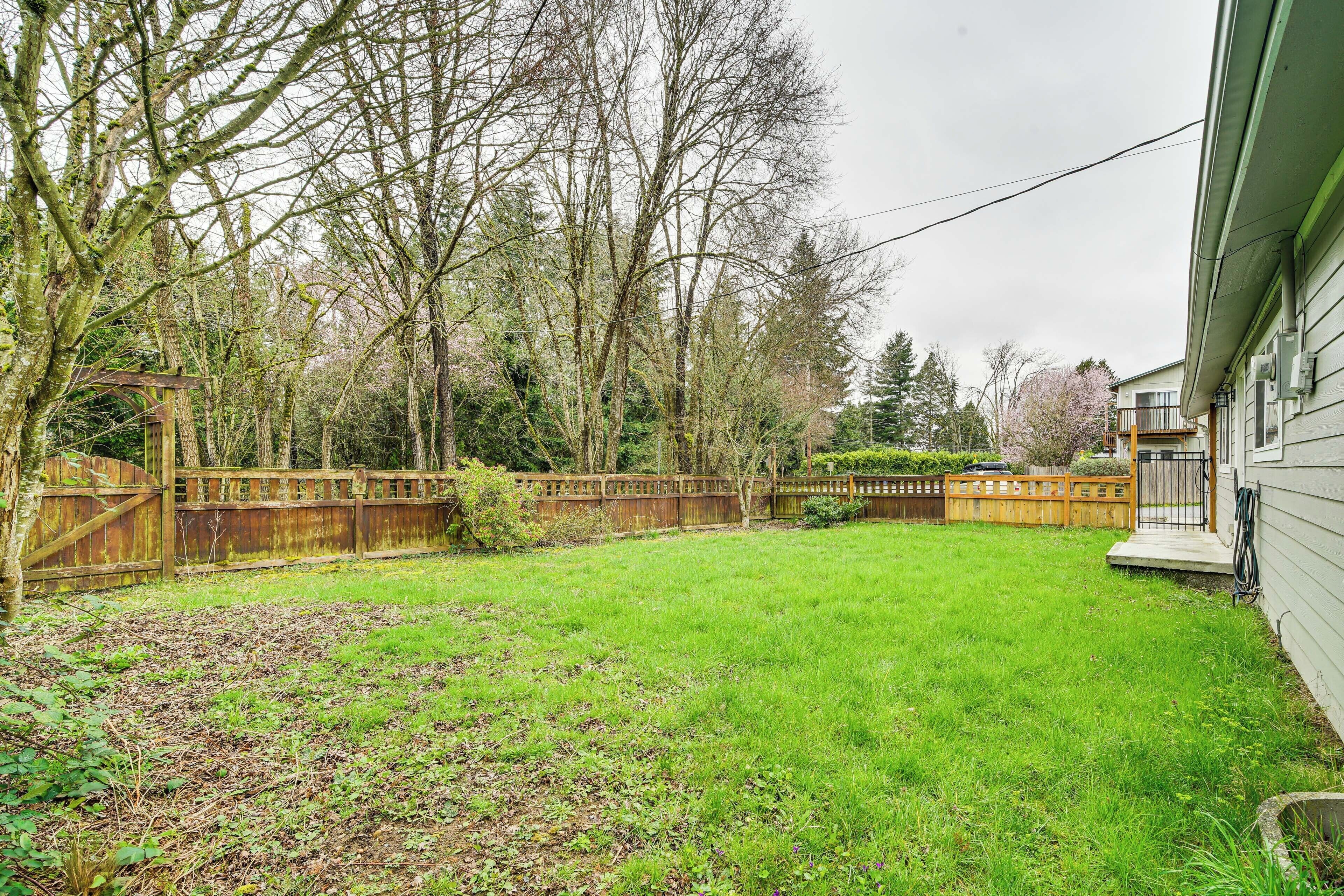 A backyard with a wooden fence, a small wooden structure, and a grassy lawn.
