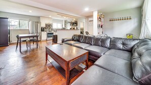 Un salon moderne avec un canapé en cuir, une table basse en bois et un coin repas.