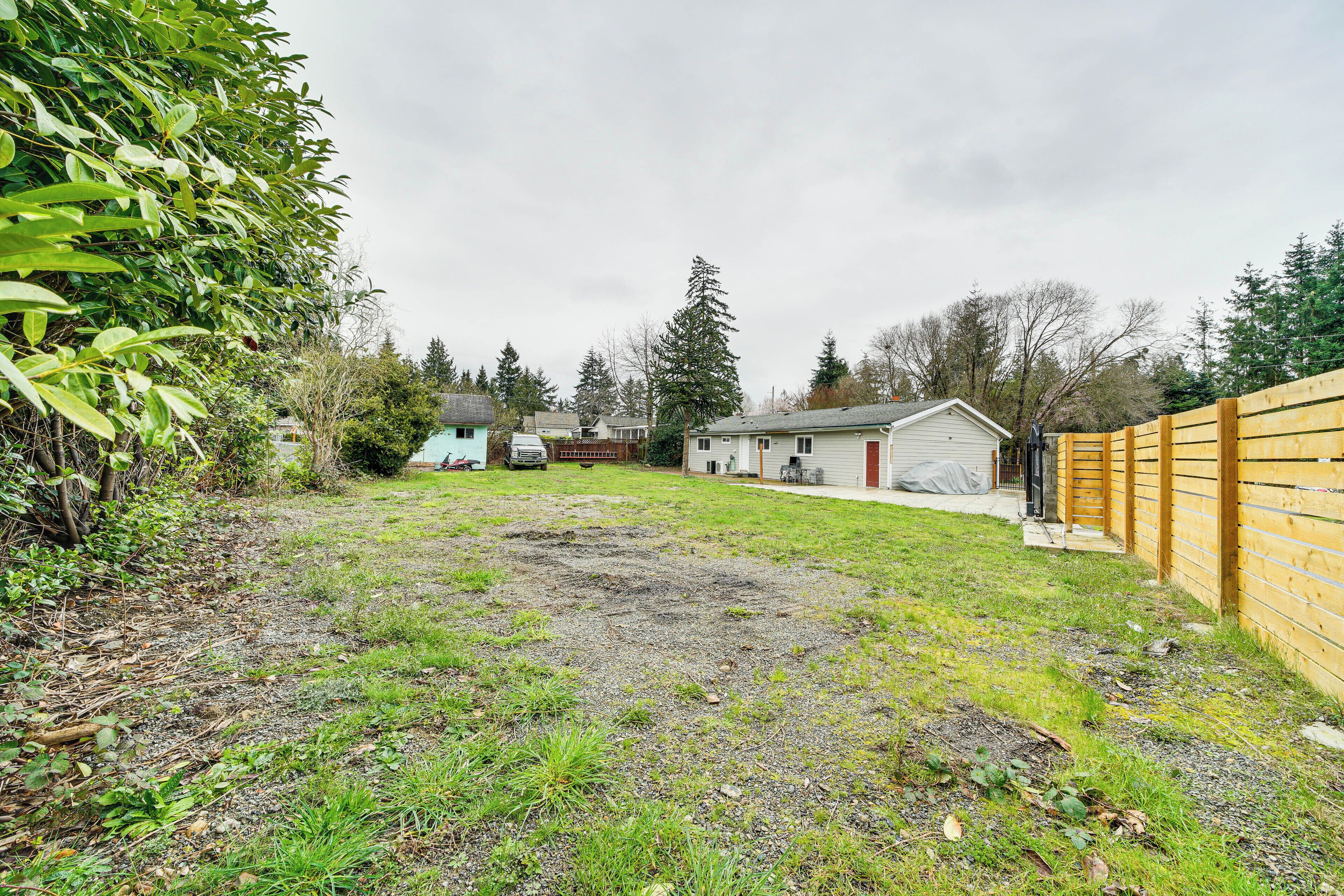A backyard with a wooden fence, a shed, and a house in the background.