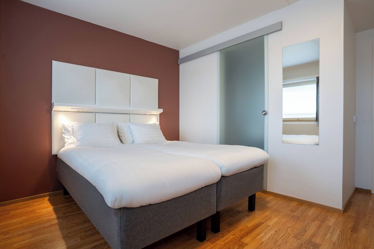 A bedroom with a bed, a wardrobe, and a sliding door to a balcony.