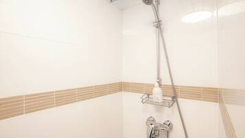 A shower with a handheld showerhead and a wall-mounted faucet.