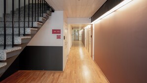 A hallway with a wooden floor, a staircase with granite steps, and a sign indicating room numbers 104-115. - Omena Hotel Hanko (Hanko)