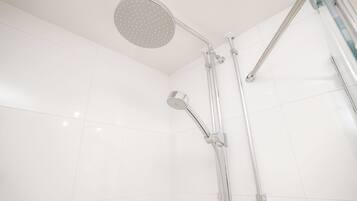 A modern shower with a handheld showerhead and a fixed overhead showerhead, both with chrome finishes.