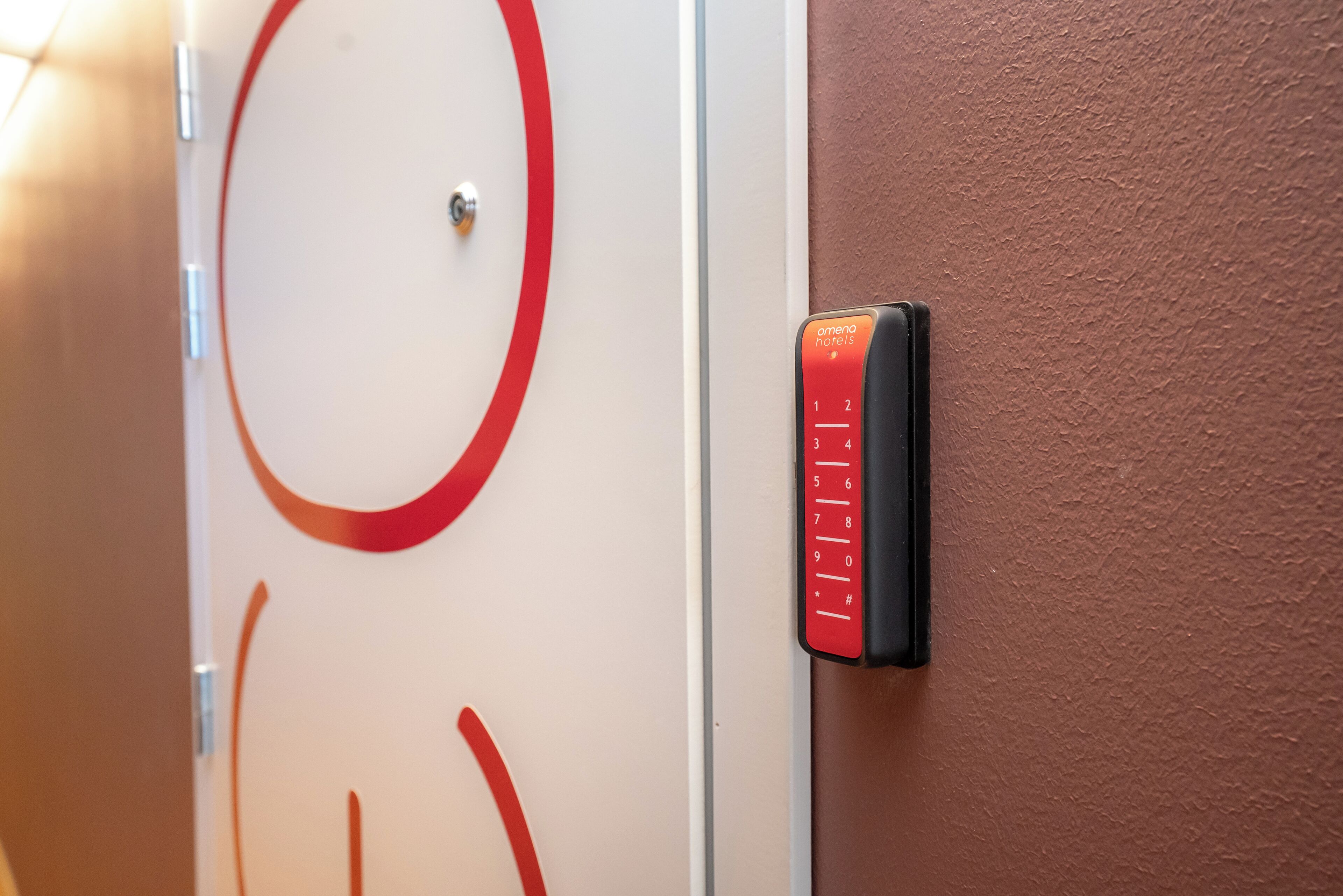 Puerta de habitación de hotel con un diseño circular rojo y cerradura electrónica.