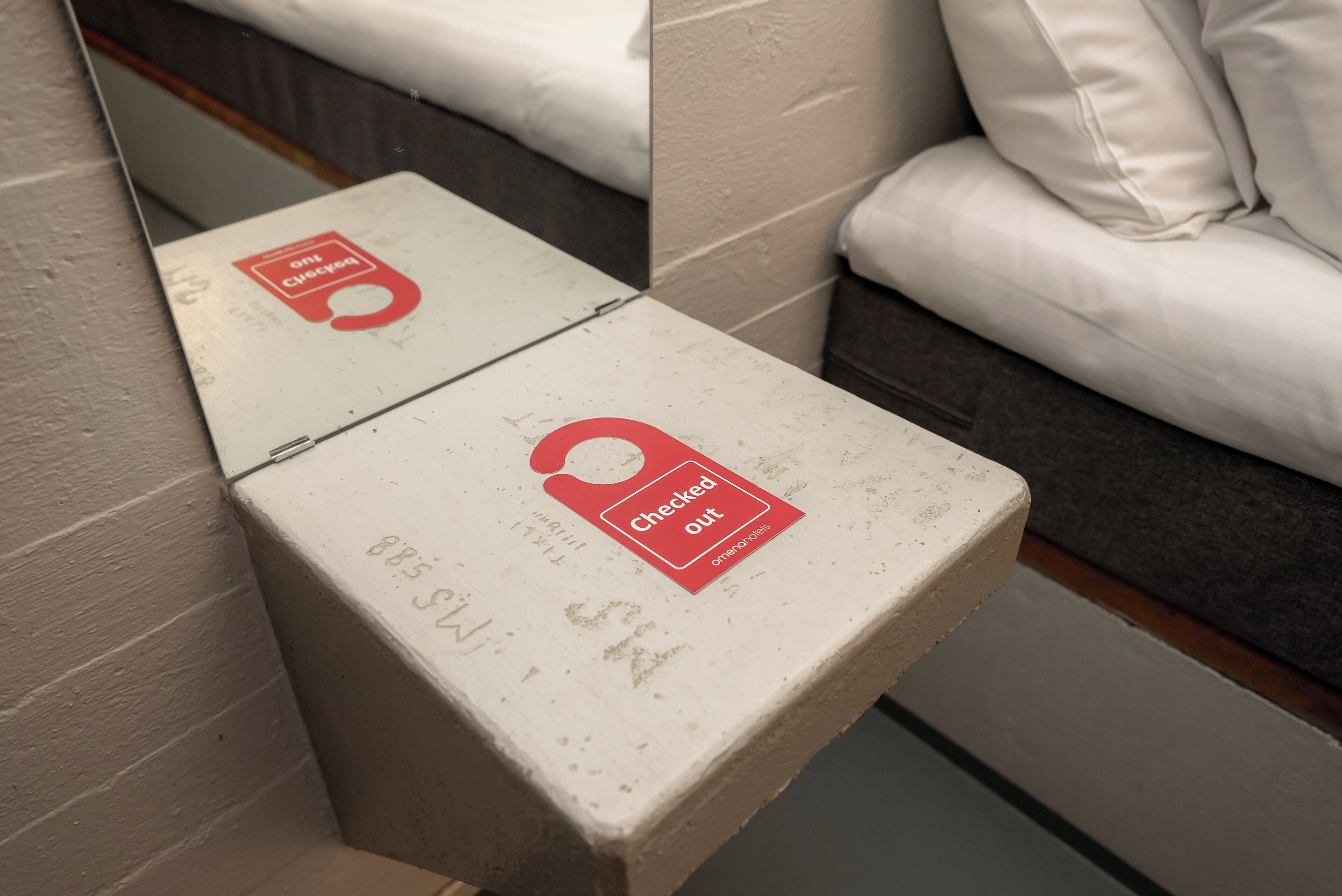 Two white boxes with red labels, one marked "Checked in" and the other "Checked out," placed against a wall near a white couch.