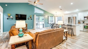 A modern kitchen with white cabinets, stainless steel appliances, and a dining area with a brown sofa and table.