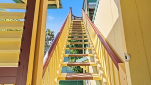 A staircase with yellow railings and a red handrail leading to a balcony.