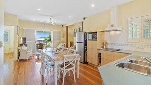 A kitchen with a dining area, wooden cabinets, a refrigerator, and a window with blinds.