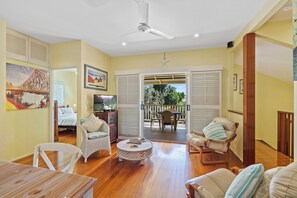 A spacious living room with a wooden floor, a ceiling fan, a television, and a dining area with a table and chairs. - Escape to your own piece of paradise at Point Lookout. (Point Lookout)
