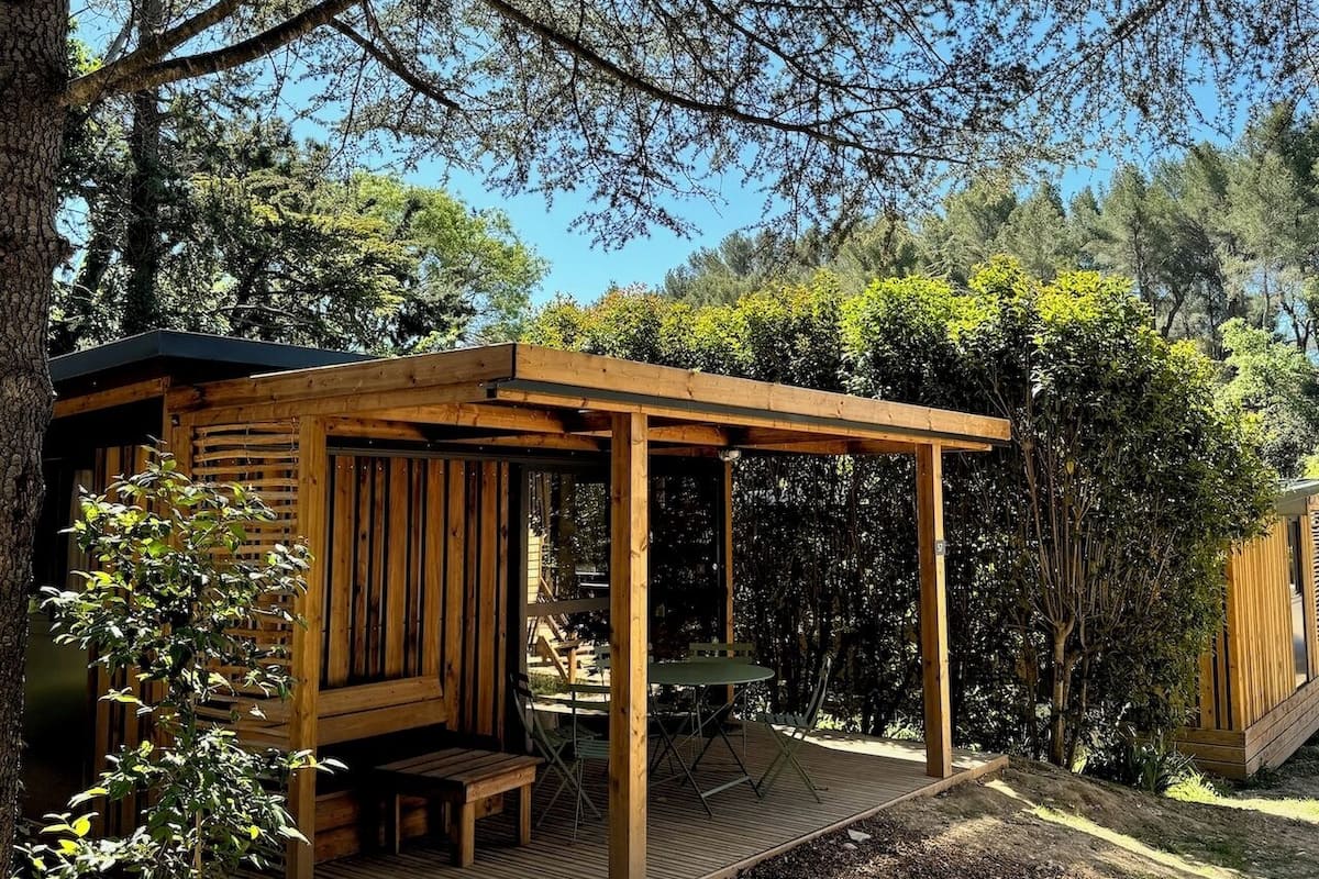 Eine Holzhütte mit überdachter Veranda, umgeben von Bäumen.