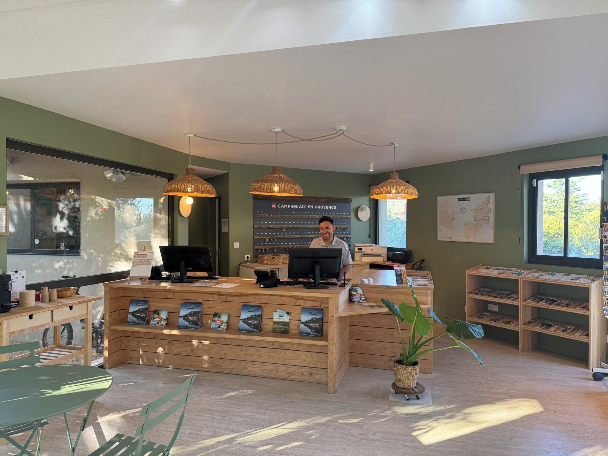 A reception desk with a computer, a map on the wall, and a plant in the center.