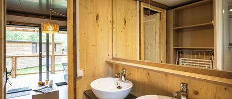 A wooden interior with two sinks, a mirror, and a wooden deck visible through an open door.