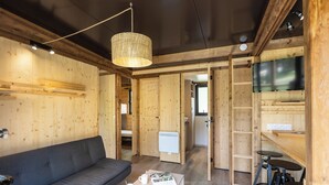 A cozy room with a sofa, a coffee table with fruit and a mug, a TV, and a wooden interior. - CityKamp d'Aix en Provence  (Aix-en-Provence)