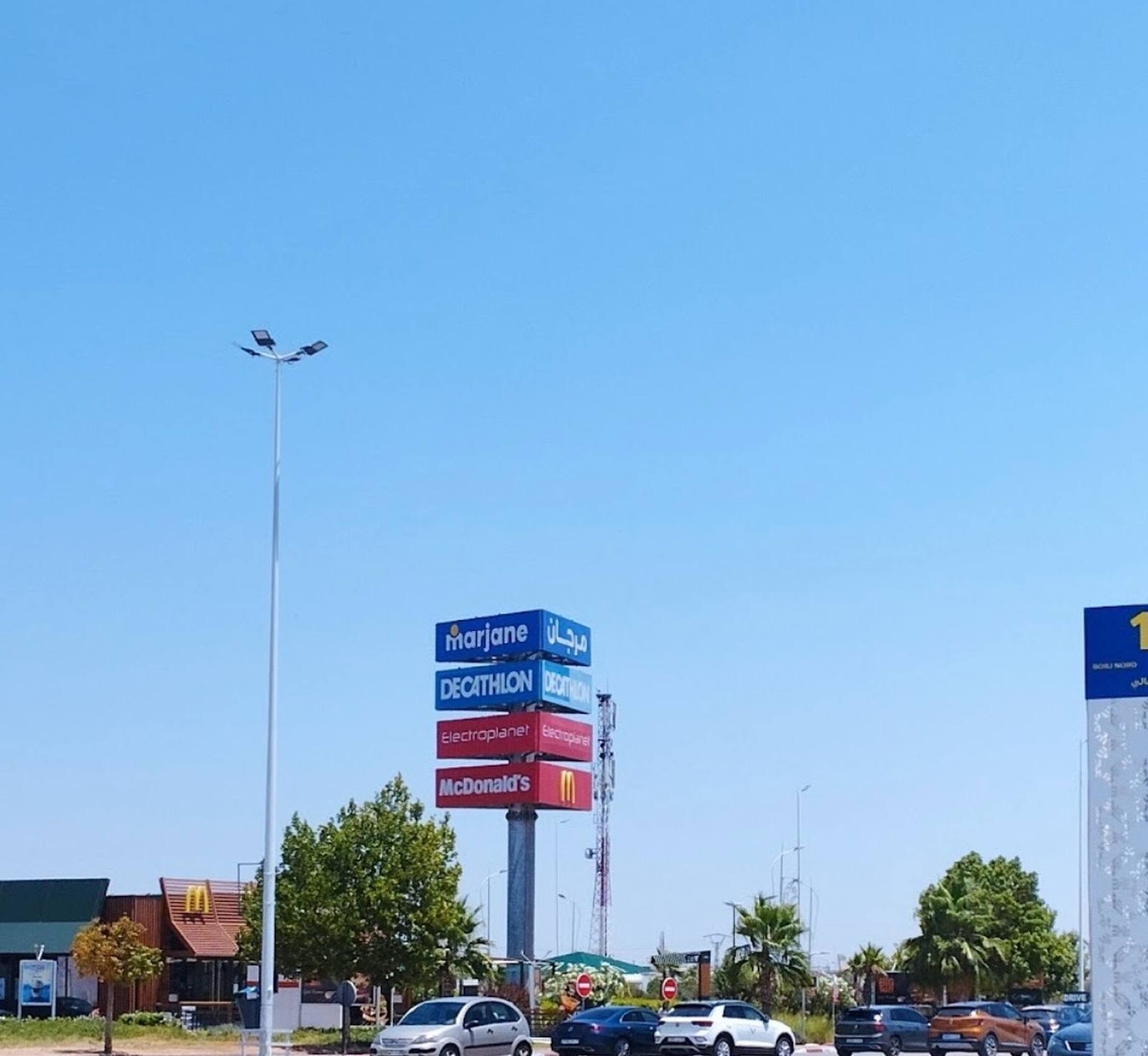 A parking lot with a signpost listing various brands.