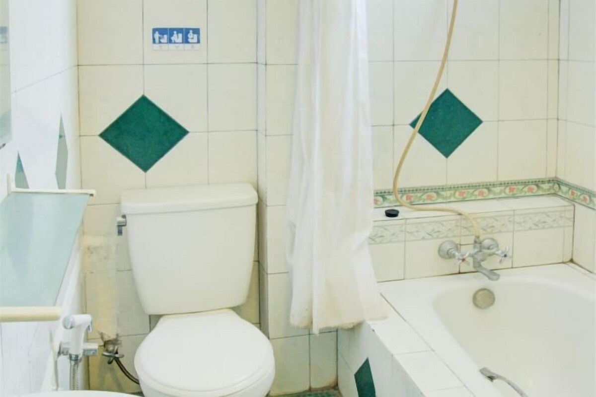 A bathroom with a toilet, bathtub, and a shower curtain.