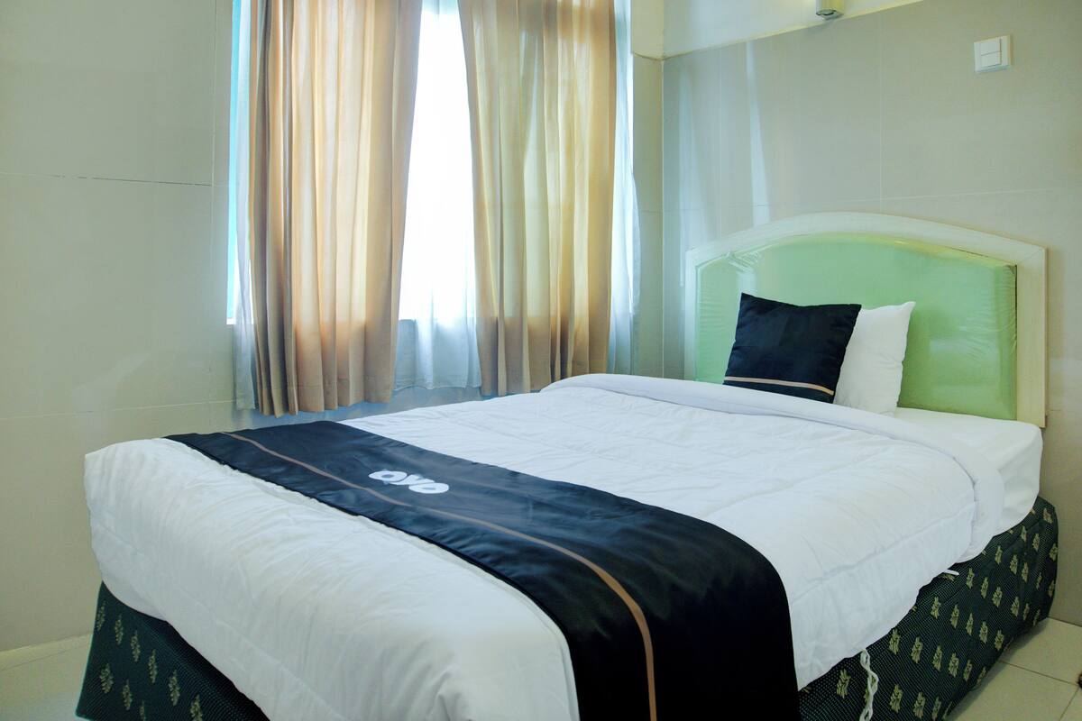 A hotel room with a bed, curtains, and a headboard.