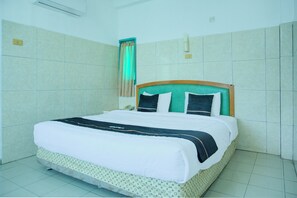 A hotel room with a bed, a telephone, and a curtain. - Townhouse Oak Palembang Near Jembatan Ampera Formerly Azzura Hotel (Palembang)