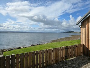 A wooden building with a view of a calm lake and distant hills. - Linden House Fortrose (Fortrose)