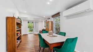 Un espace repas moderne avec une table en bois, des chaises à revêtement vert et une bibliothèque en bois.