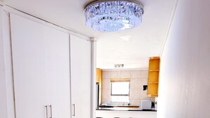 A modern kitchen with white cabinets, a central island, and red bar stools. - Spacious 1 Bedroom Apartment Atlantica Seapoint (Cape Town)