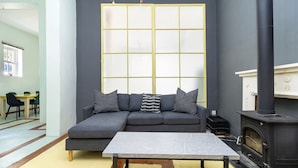A modern living room with a sectional sofa, a coffee table, a fireplace, and a large window with a grid pattern.