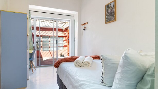 A bedroom with a bed, a window, and a view of an outdoor area.