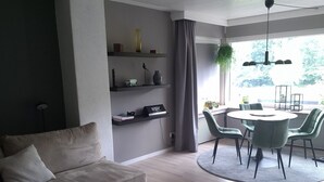 A modern living room with a sofa, a coffee table, and a dining area with chairs and a table.