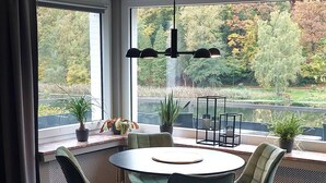 A dining area with a round table, four chairs, and a hanging light fixture.