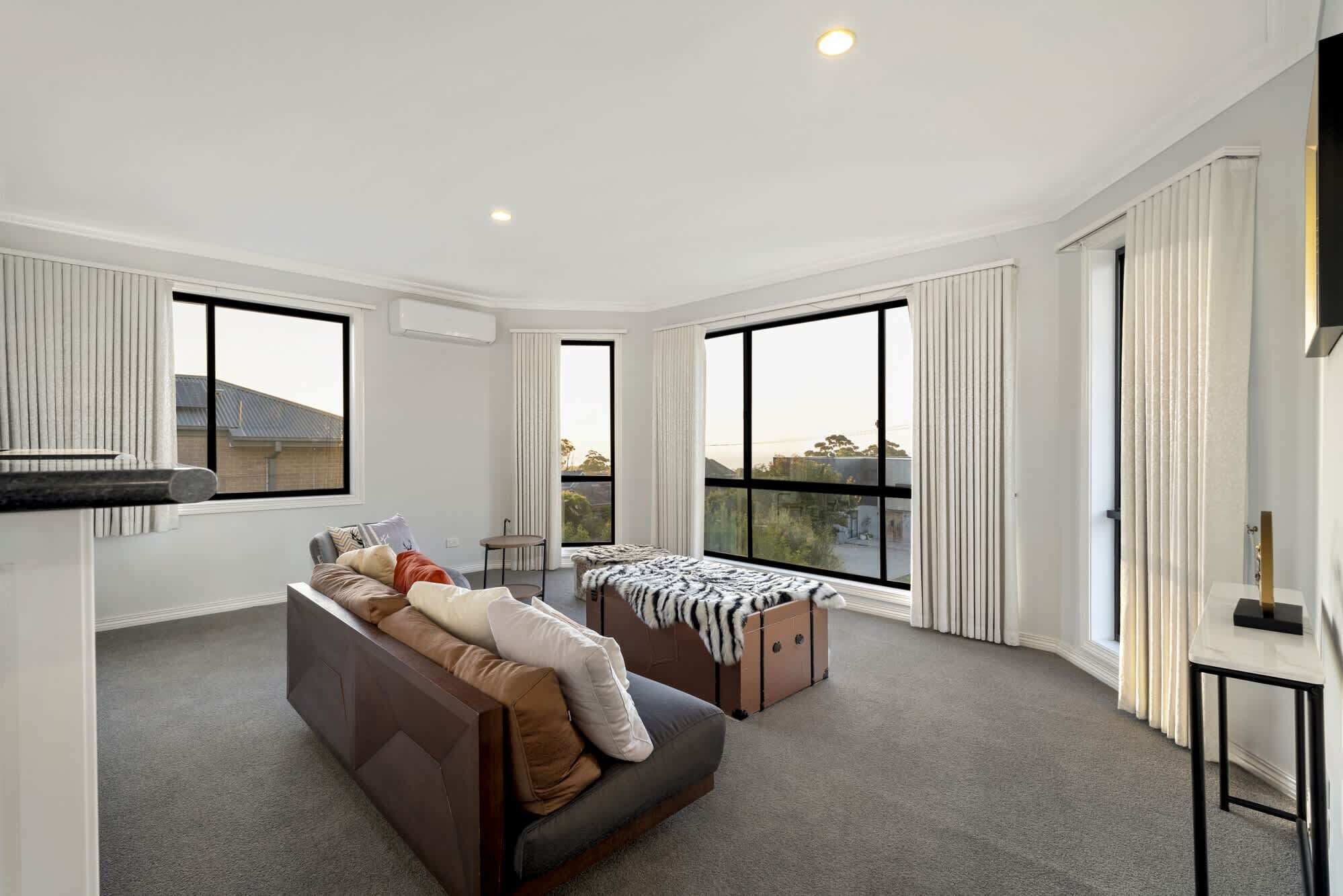A spacious living room with a large window, a sofa, a small table, and a cabinet.