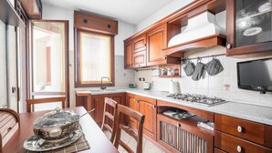 Una cocina con armarios de madera, estufa a gas, microondas y una mesa de comedor con sillas.