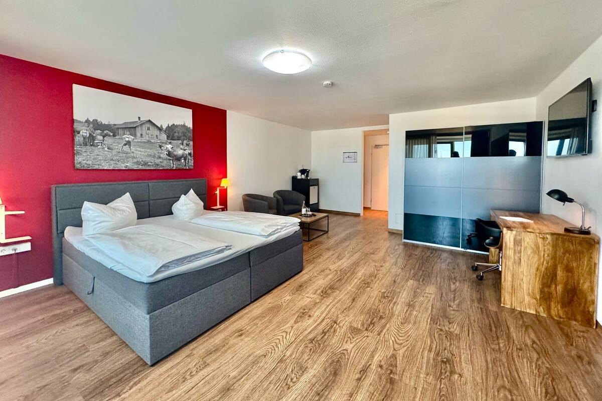 A modern hotel room with a large bed, a desk, a chair, and a television.