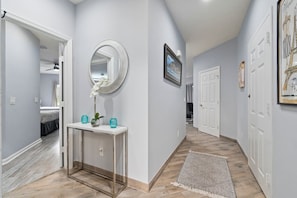 A hallway with a white console table, a mirror, and a door leading to a bedroom.
