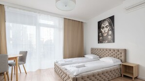Une chambre à coucher avec un grand lit, une table de chevet, une chaise et une fenêtre avec des rideaux.