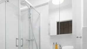 Une salle de bain moderne avec une douche à parois de verre, un meuble-lavabo blanc avec un miroir et des toilettes.