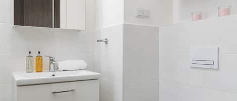 A modern bathroom with a white vanity, a toilet, and a shower area.