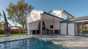 A modern house with a swimming pool, outdoor seating area, and a covered patio.