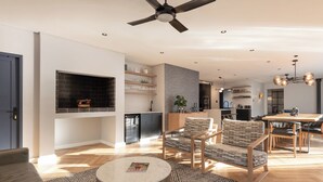 A modern living room with a fireplace, a dining area with wooden furniture, and a kitchen with a built-in oven.