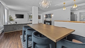 Een moderne keuken met een houten kookeiland, barstoelen, hanglampen en een groot raam.